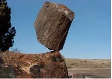 Precariously  - In a way that is not securely in position and is likely to fall or collapse.