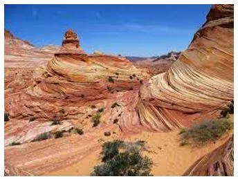 Erode - Gradually wear away (soil, rock, or land). (घिस)