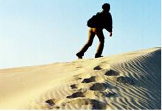 Plod  - Walk doggedly and slowly with heavy steps.